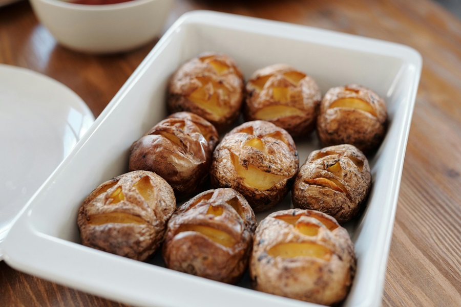 Baked Potatoes in the Oven a baking Dish of Baked Potatoes on a Wooden Table