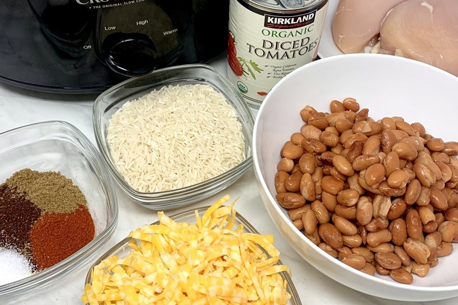 Easy Chicken Burrito Bowl Recipe Ingredients Separated Into Bowls in Front of a Crock Pot on a Counter Top