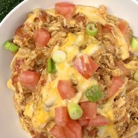 Easy Chicken Burrito Bowl Recipe Close Up of a Burrito Bowl Topped with Cheese, Green Onions, and Diced Tomatoes