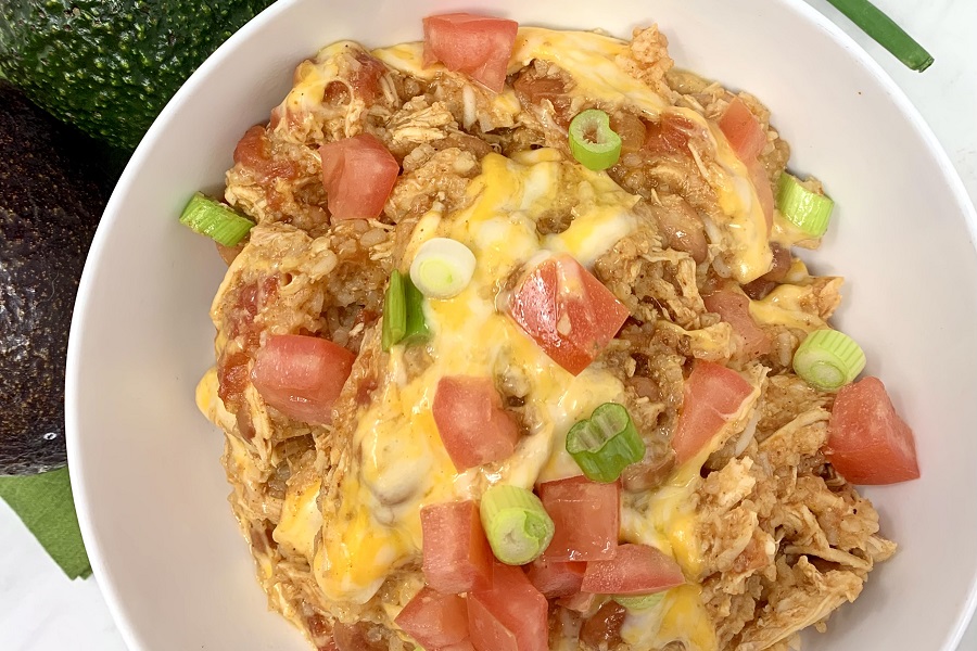 Easy Chicken Burrito Bowl Recipe Close Up of a Burrito Bowl Topped with Cheese, Green Onions, and Diced Tomatoes