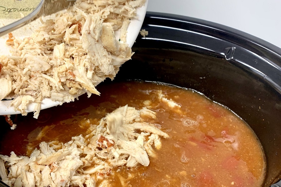 Easy Chicken Burrito Bowl Recipe Shredded Chicken Being Poured into a Crock Pot