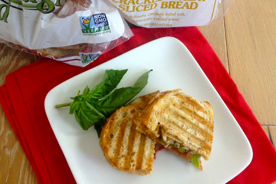 Pizza Sandwich Recipe Close Up of a Sandwich Cut in Half on a White Plate with a Sprig of Basil