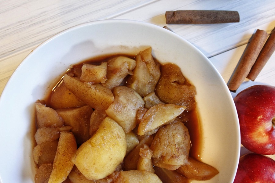 Faster Than Stovetop Instant Pot Cinnamon Apples Recipe in a Bowl Next to Cinnamon Sticks and Apples