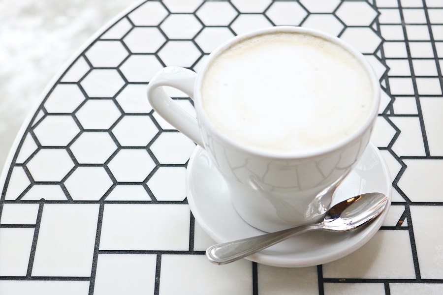 High Protein Grocery List Close Up of a Cup of Milk on a Saucer with a Small Spoon