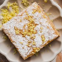 Lemon Bar Recipe Lemon Bar on a Plate Dusted with Powders Sugar and Lemon Zest