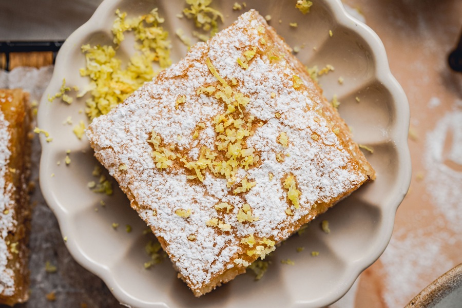 Lemon Bar Recipe Lemon Bar on a Plate Dusted with Powders Sugar and Lemon Zest