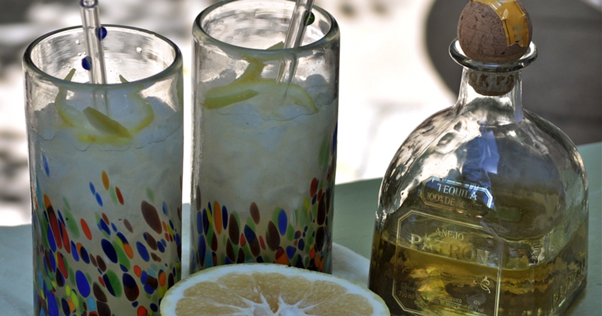 National Margarita Day Recipes A Bottle of Patron Next to Two Glasses of Grapefruit Patron Margaritas and a Half a Grapefruit