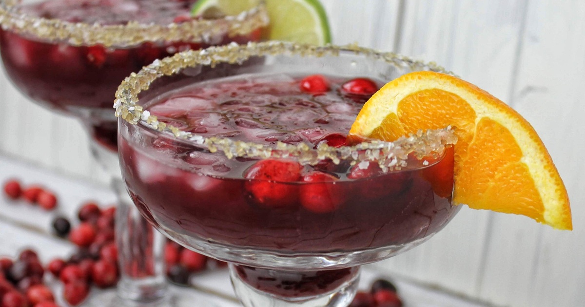 National Margarita Day Recipes Close Up of a Cranberry Margarita Garnished with an Orange Wedge and Cranberries