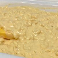 Simple Macaroni and Cheese Recipe Close Up of Macaroni and Cheese Inside a Crockpot with a Yellow Spoon Inside