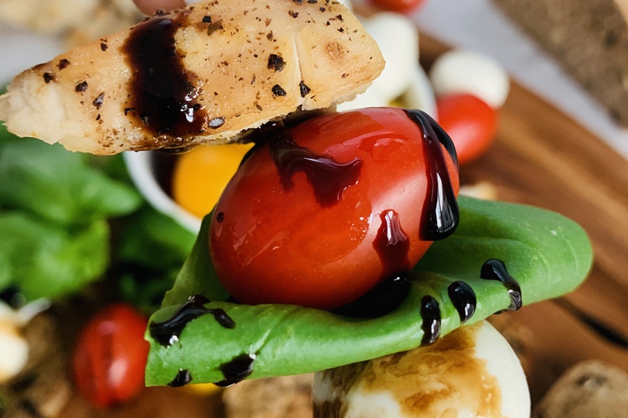 Easter Appetizers Close Up of Caprese Chicken Skewers with Roma Tomatoes and Spinach Drizzled with Balsamic Vinaigrette 