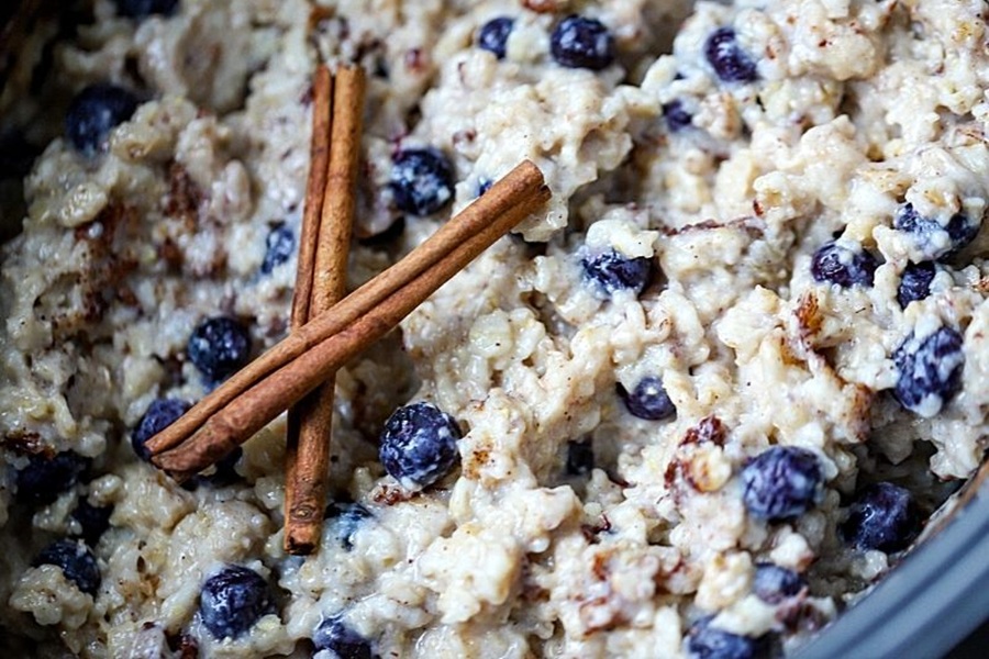 Crockpot Mother's Day Brunch Recipes Close Up of Easy Blueberry Crockpot Oatmeal Garnished with Two Cinnamon Sticks and Blueberries