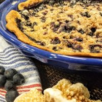 Close Up of a Blueberry Pie in a Blue Dish with Blueberries Next to it