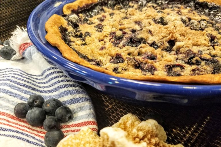 Close Up of a Blueberry Pie in a Blue Dish with Blueberries Next to it