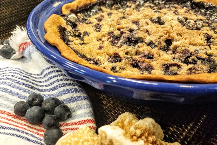 Close Up of a Blueberry Pie in a Blue Dish with Blueberries Next to it