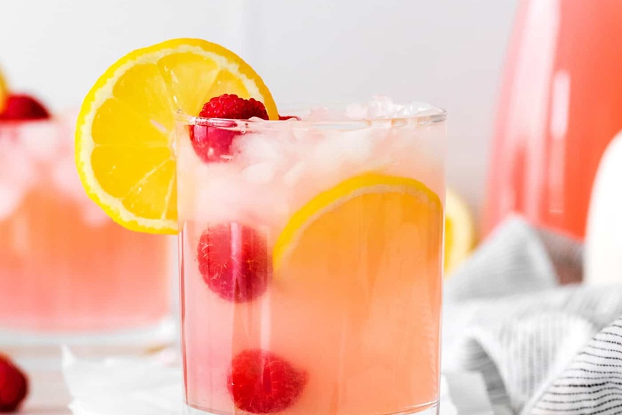 Summer Margarita Recipes Pink Lemonade Margarita with a Lemon Slice on the Rim and Raspberries in the Drink