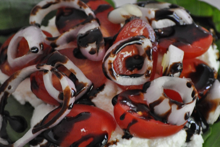 Portobello Mushroom Burger Close Up of Onions, Cherry Tomatoes, and Cheese Drizzled with Balsamic Vinaigrette 