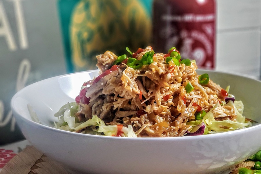 Slow Cooker Hawaiian Chicken Close Up of Hawaiian Chicken Topped with Scallions and Hot Sauce with a Bottle of Sriracha in the Background