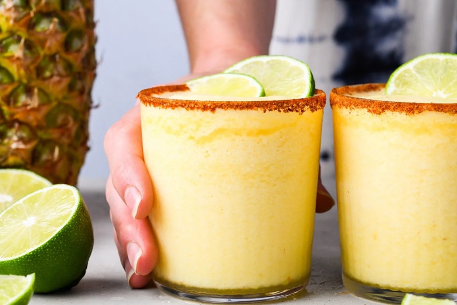 Summer Margarita Recipes A Person's Hand Pushing Forward a Frozen Orange Pineapple Margarita