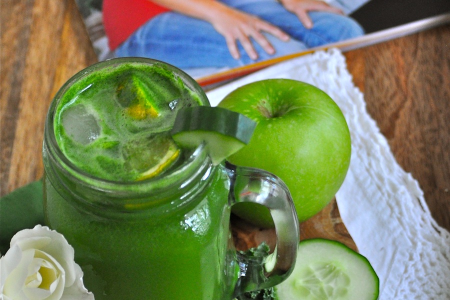 Jillian Michael&rsquo;s Green Juice Recipe in a Mason Jar Glass with an Apple and Cucumber Slices in the Background and a Fitness Magazine