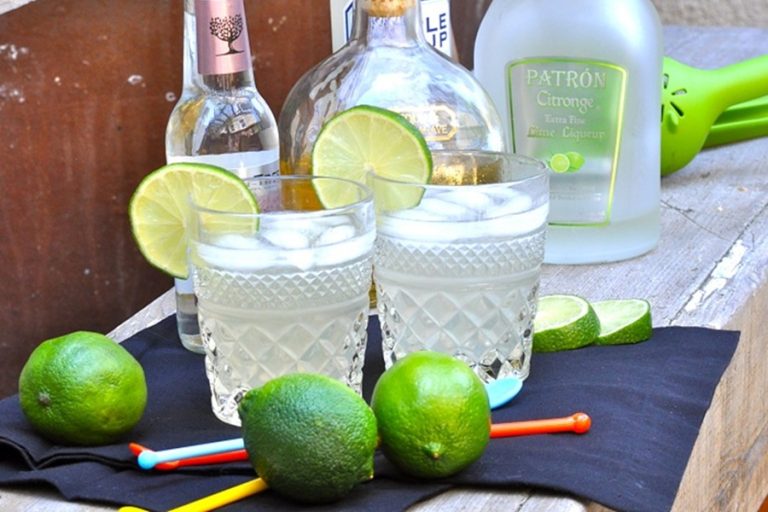 Low Carb Margarita Recipe Two Margaritas in Glasses Garnished with Lime Slices Two Limes in Front and Bottles of Alcohol in the Background