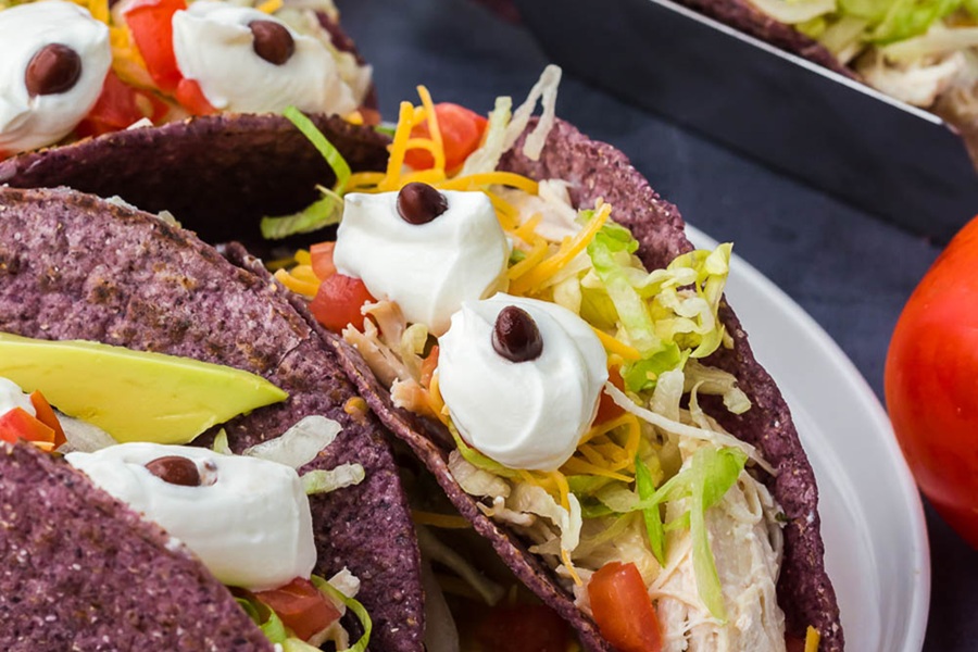 Crockpot Halloween Recipes a Plate of Tacos in Purple Taco Shells with Sour Cream Dollops Made to Look Like Eyes