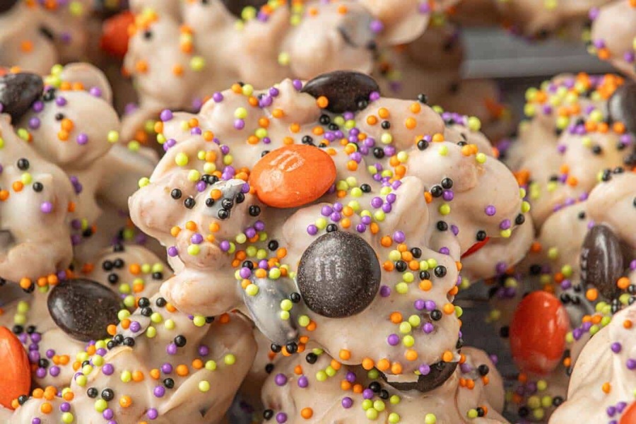 Crockpot Halloween Recipes White Chocolate Clusters Covered in Green, Orange, and Purple Sprinkles and Orange and Brown M&Ms
