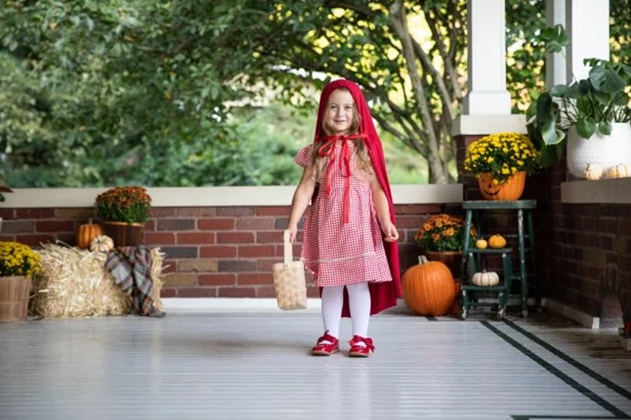 DIY Halloween Costumes For Kids a Little Girl Wearing a Red and White Dress, a Red Hooded Cape, and Holding a Picnic Basket