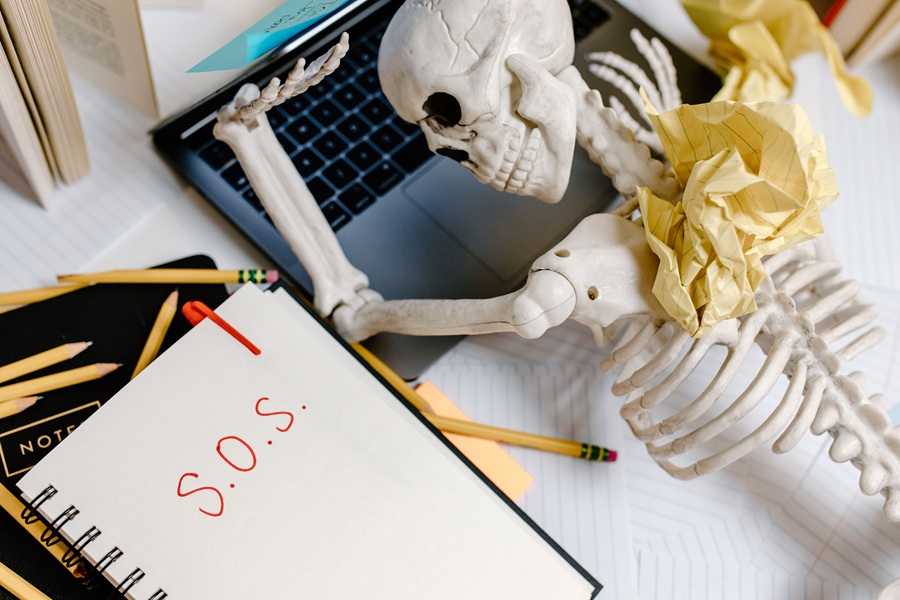 Downloads for your Halloween Playlist a Skeleton Laying on a Laptop with a Piece of Paper Next to it That Says S.O.S.