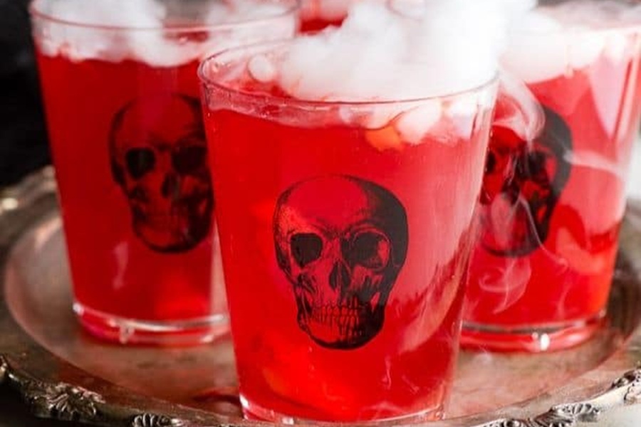 Spooky Halloween Crockpot Recipes Close Up of Red Punch in Plastic Cups with Black Skulls Printed on Them