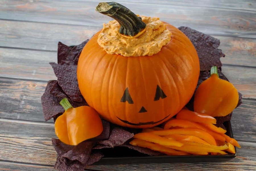 Spooky Halloween Crockpot Recipes a Pumpkin Overflowing with Buffalo Dip on a Platter with Tortilla Chips
